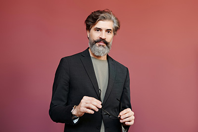 man in blazer holding glasses
